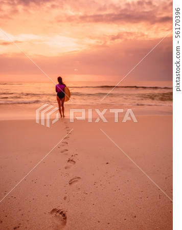 Surfer woman with surfboard on beach at sunset Surfer woman with surfboard on beach at sunset 56170396
