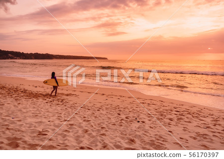 Surfer woman with surfboard on beach at sunset Surfer woman with surfboard on beach at sunset 56170397