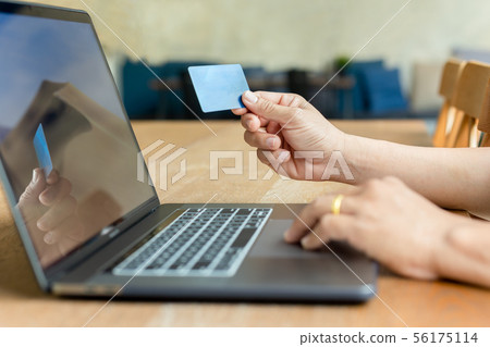 Businessman hand holding credit card and using laptop on wooden table. Businessman hand holding credit card and using laptop on wooden table. 56175114