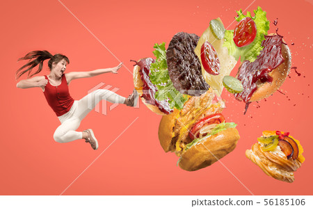 Fast food concept. Young woman fight with burger on red background 56185106