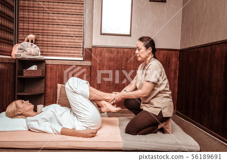Happy woman having her feet massage in thai massage salon. 56189691