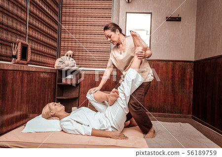 Thai woman doing leg massage for her client. Thai woman doing leg massage for her client. 56189759