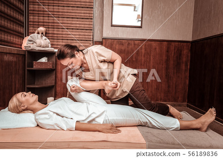 Strong masseuse doing thai massage for her client. Strong masseuse doing thai massage for her client. 56189836