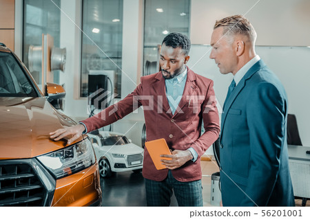 Car dealer talking about pros of the automobile. Car dealer talking about pros of the automobile. 56201001