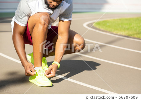 Serious bearded African American athletic man tying laces Serious bearded African American athletic man tying laces 56207609