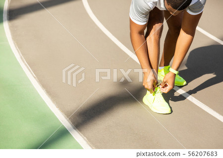 Young male athlete tying laces at the stadium Young male athlete tying laces at the stadium 56207683
