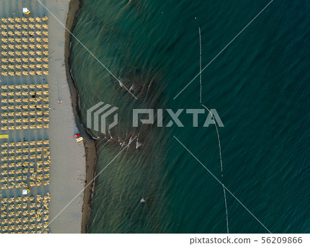 Aerial view of sandy beach with yellow sunbeds and wooden umbrellas at sunset 56209866