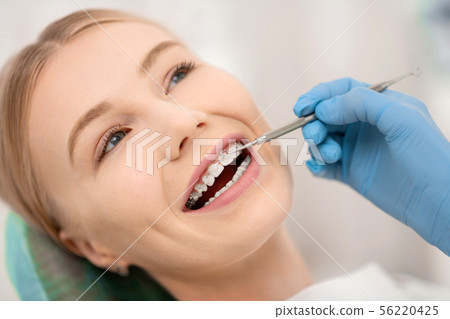 Patient fixing her orthodontic braces in dental clinic. Patient fixing her orthodontic braces in dental clinic. 56220425