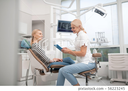 Dentist talking to her client before the procedure. 56223245