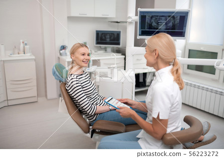Dentist consulting her patient about future appointments. 56223272