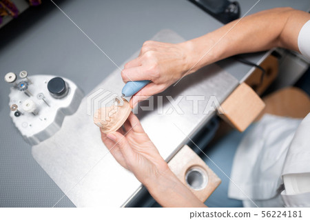 Dental technician making dental prosthesis looking better. Dental technician making dental prosthesis looking better. 56224181