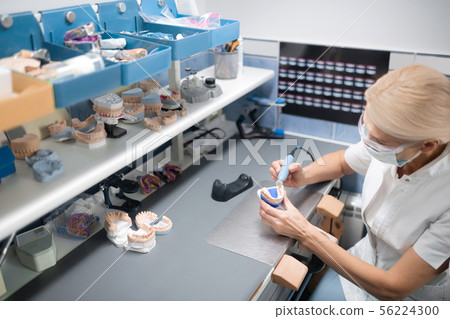 Dental technician working in her office full of equipment. 56224300