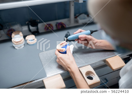 Dental technician doing denture polishing in her office. 56224410