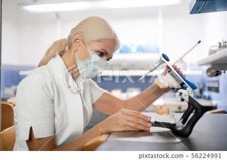Dentist looking closely at cast model of patients teeth. 56224991