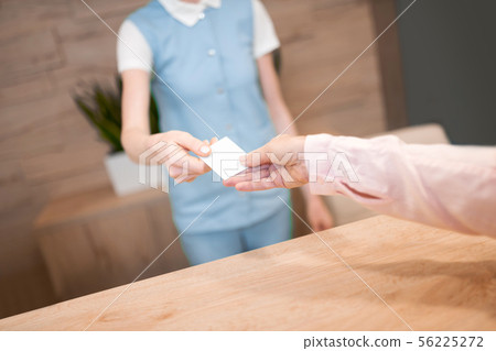 Administrator giving the patient business card of dental clinic. Administrator giving the patient business card of dental clinic. 56225272