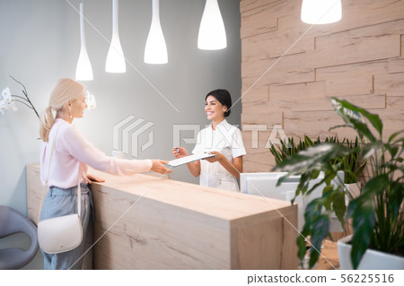 Woman standing at reception of dental clinic. 56225516