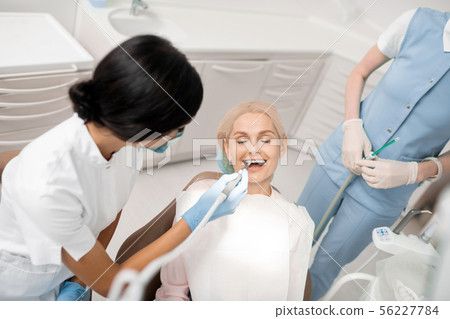 Cheerful woman getting her teeth treatment in dental clinic. Cheerful woman getting her teeth treatment in dental clinic. 56227784