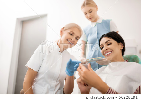 Dentist helping her patient choosing teeth whitening samples. 56228191