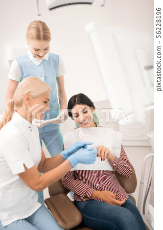 Dentist showing her patient teeth whitening samples. 56228196