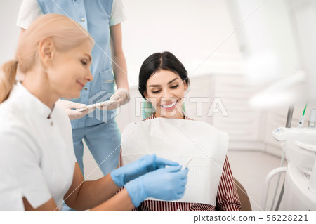 Cheerful woman looking at teeth whitening samples. Cheerful woman looking at teeth whitening samples. 56228221