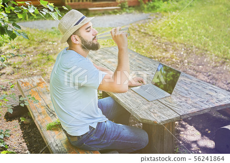 Businessman is working with computer in forest. Businessman is working with computer in forest. 56241864