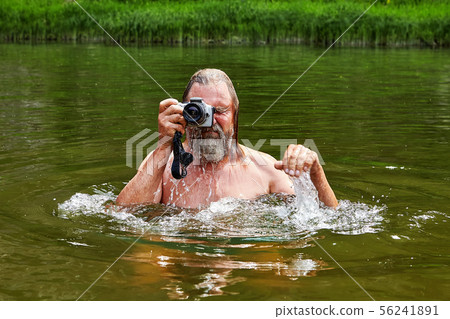 Wet man takes photos in river. Wet man takes photos in river. 56241891