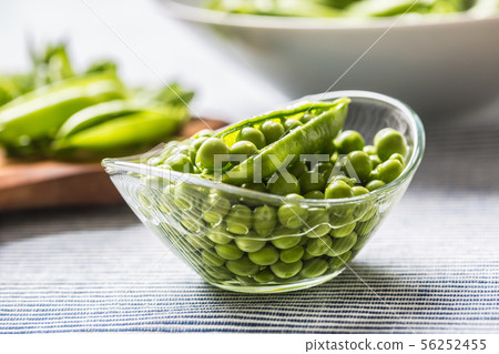 Fresh green pea seeds in bowl on kitchen table Fresh green pea seeds in bowl on kitchen table 56252455