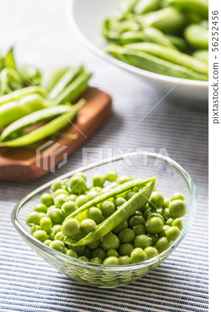 Fresh green pea seeds in bowl on kitchen table 56252456