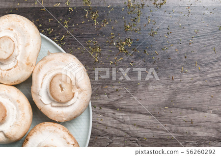 Close-up of white mushrooms on a white plate on a dark wooden table. Vegetarian healthy food 56260292