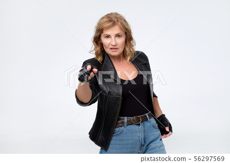 Angry woman in leather jacket pointing finger at camera 56297569