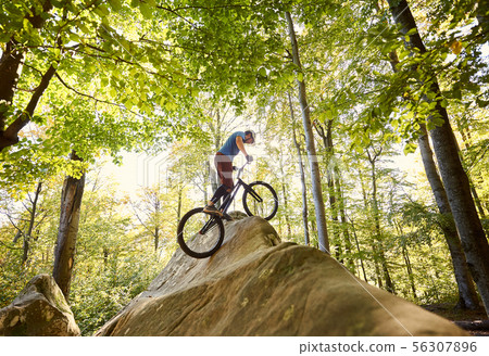 Male cyclist on trial bicycle on the top of boulder outdoors 56307896