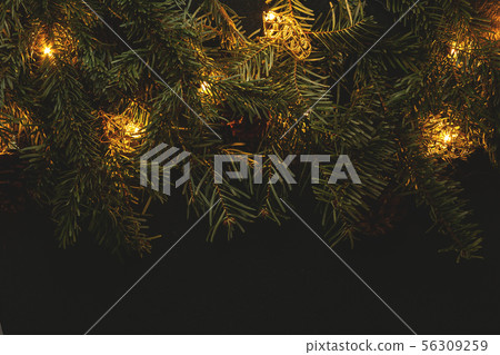 Christmas composition, branches of a Christmas tree on a dark background with lights 56309259