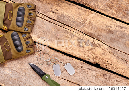 Military gloves, knife and dog tags on wood with copyspace. 56315427