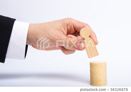 A man's hand puts a person's figure on top A man's hand puts a person's figure on top 56326878