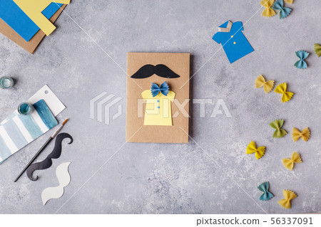 Making greeting card for Fathers Day. Shirt with butterfly from pasta. Card from paper. moustache 56337091