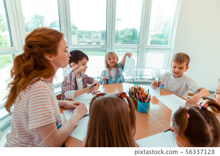 Delighted positive girl showing her drawing to the teacher 56337128