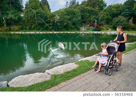 young mother with her daughter in a stroller by 56338468