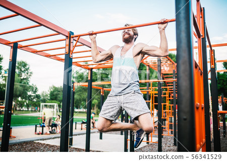 strong athlete doing pull-up on horizontal bar. Muscular man doing pull ups on horizontal bar in strong athlete doing pull-up on horizontal bar. Muscular man doing pull ups on horizontal bar in 56341529