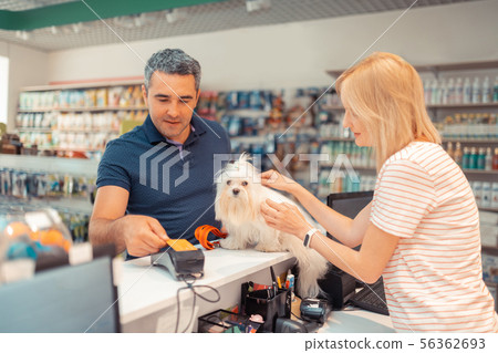 Grey-haired man paying for white dog for daughter by card 56362693