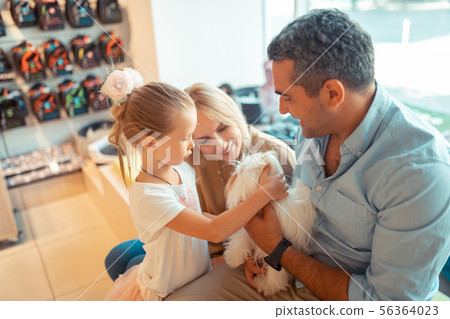 Daughter coming to pet shop with parents and holding dog 56364023