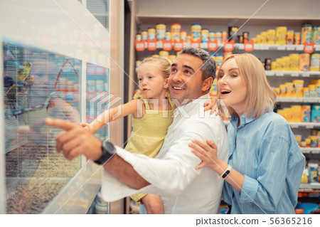 Blue-eyed girl feeling happy seeing parrots with parents 56365216