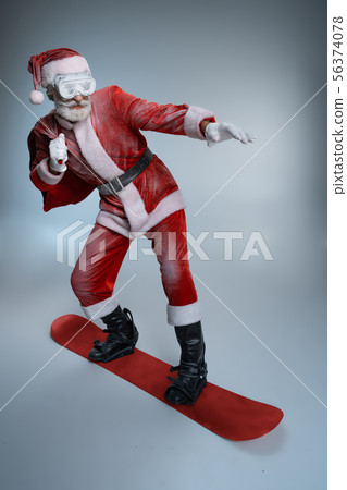 Senior Santa Claus holding sack, standing on snowboard Senior Santa Claus holding sack, standing on snowboard 56374078