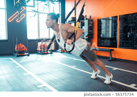 Smart handsome man focusing on his trx workout Smart handsome man focusing on his trx workout 56375734