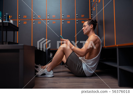 Pleasant fit man sitting on the floor 56376018