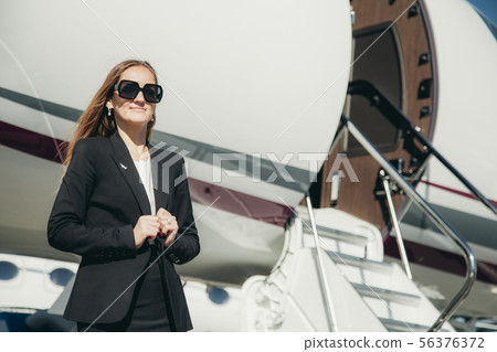 beautiful young business woman near the airplane jet at sunny day in airport 56376372