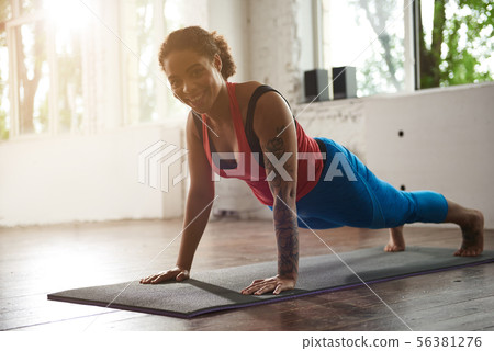 Pretty smiling woman doing plank in gym Pretty smiling woman doing plank in gym 56381276