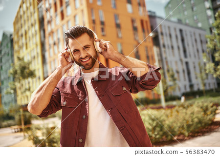 Good mood. Handsome and happy young man with stubble in headphones listening to the music and Good mood. Handsome and happy young man with stubble in headphones listening to the music and 56383470
