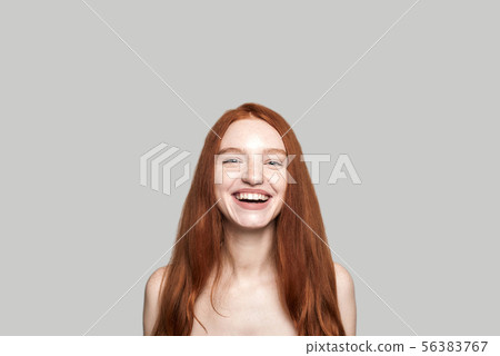 Cheerful beauty. Portrait of positive and pretty young redhead lady smiling at the camera while 56383767