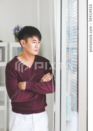 Man standing and crossed his arms near window.. 56414918