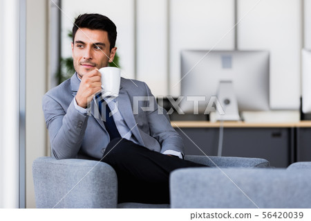 Businessman drinking coffee in office.. Businessman drinking coffee in office.. 56420039